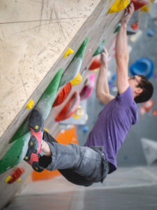 A climber hooking a toe around a hold before the next move
