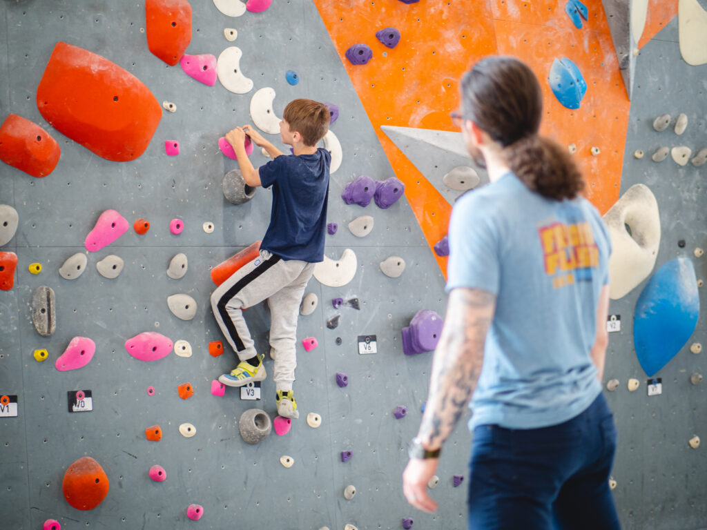 An adult supervising a child bouldering
